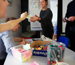 Photo représentant un atelier participatif. Une personne tend un post-it à l'animatrice.